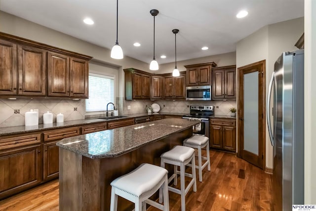 kitchen featuring a sink, appliances with stainless steel finishes, a kitchen island, and wood finished floors