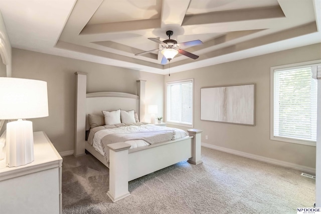 bedroom with a raised ceiling, multiple windows, and light carpet