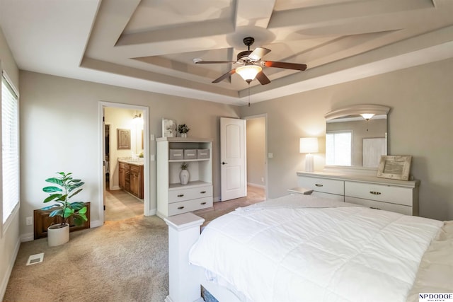 bedroom with visible vents, baseboards, light colored carpet, connected bathroom, and a tray ceiling