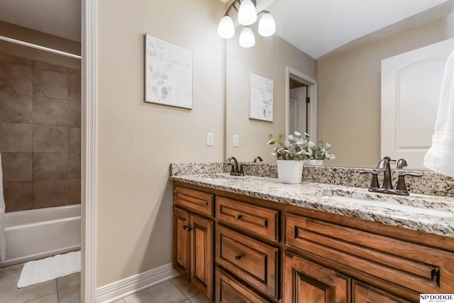 bathroom with baseboards, double vanity, tile patterned floors, and a sink