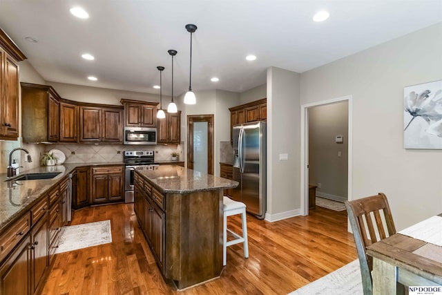 kitchen with a center island, a sink, dark stone countertops, dark wood-style floors, and stainless steel appliances