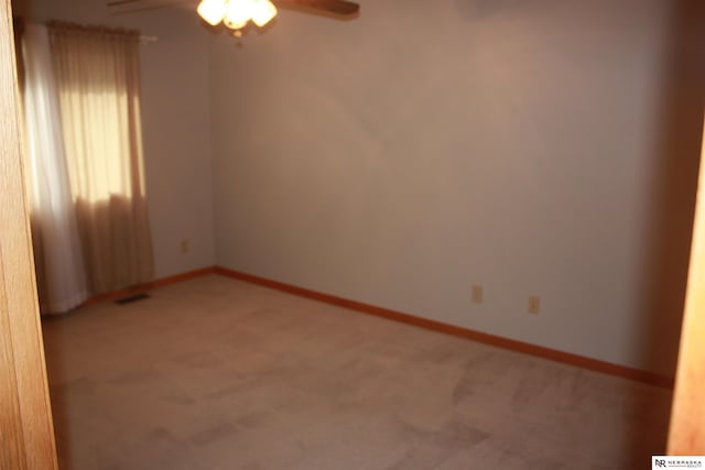 spare room featuring baseboards, ceiling fan, and light carpet