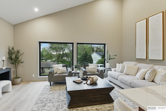 living room with baseboards, recessed lighting, wood finished floors, and high vaulted ceiling
