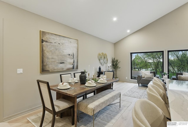 dining room with light wood-type flooring, recessed lighting, baseboards, and high vaulted ceiling