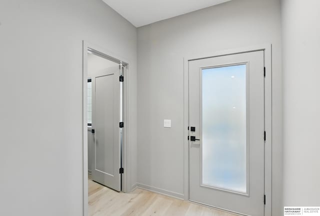 doorway to outside featuring baseboards and light wood finished floors