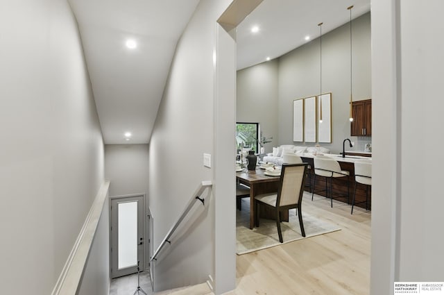 hallway featuring light wood-style floors, a high ceiling, and recessed lighting