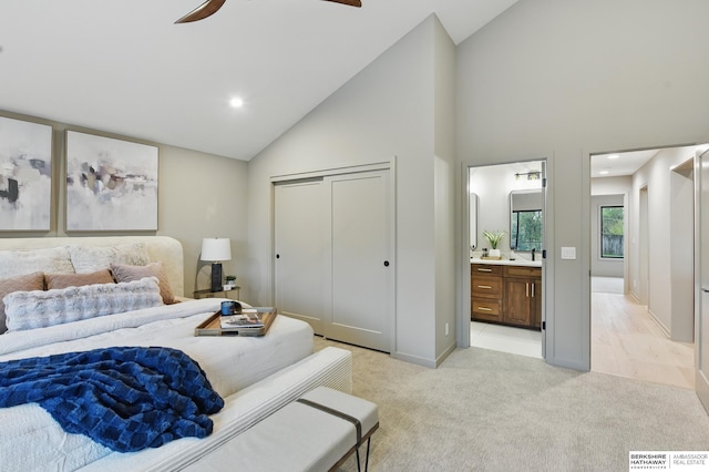 bedroom with a closet, light carpet, ceiling fan, high vaulted ceiling, and ensuite bath