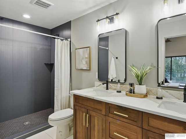 bathroom featuring double vanity, visible vents, a tile shower, and a sink