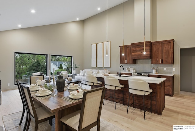 dining room featuring recessed lighting, light wood-type flooring, and a towering ceiling