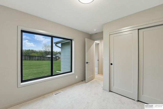 unfurnished bedroom with visible vents, baseboards, a closet, and light colored carpet
