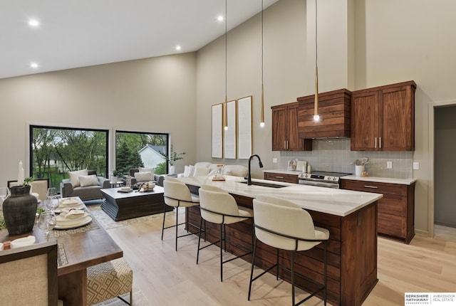 kitchen featuring a sink, light wood-style floors, light countertops, high vaulted ceiling, and electric stove