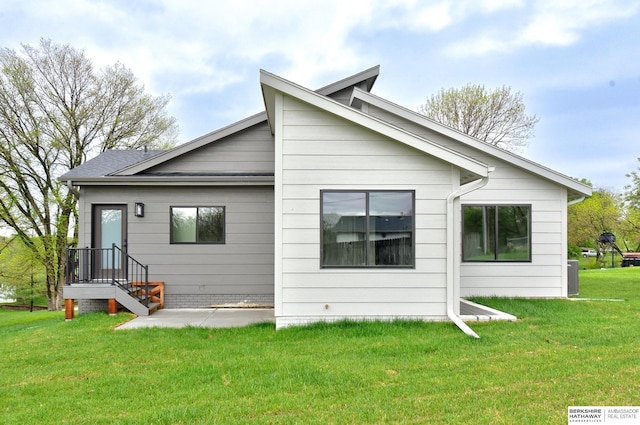 back of house featuring roof with shingles, a yard, and central AC