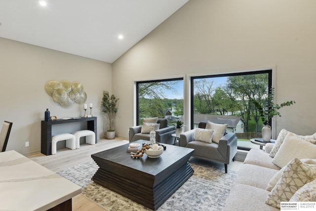 living area with high vaulted ceiling, baseboards, recessed lighting, and light wood-style flooring