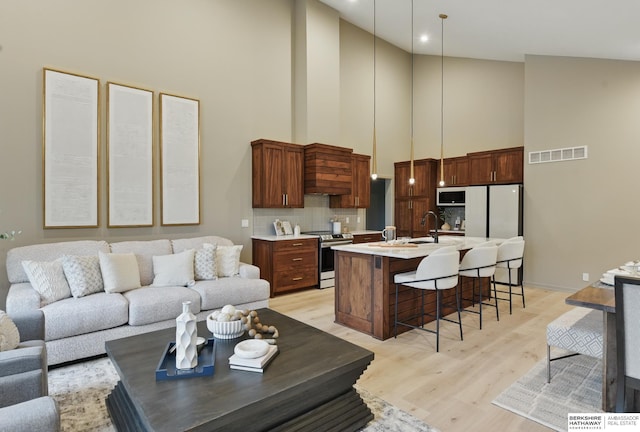 kitchen featuring white appliances, a kitchen breakfast bar, high vaulted ceiling, light countertops, and visible vents