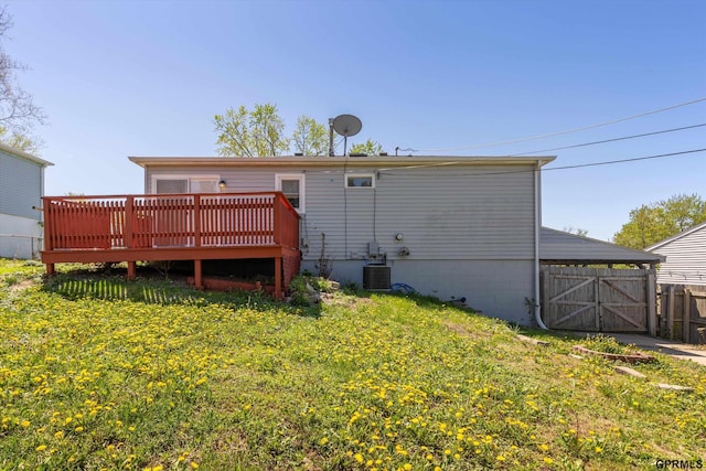 rear view of property featuring a lawn, a deck, a gate, central air condition unit, and fence