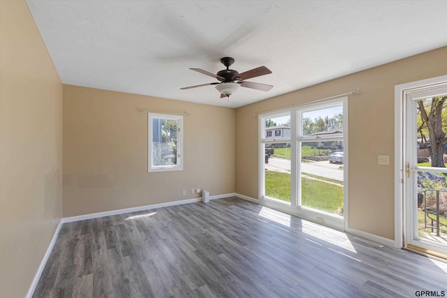 unfurnished room with plenty of natural light, baseboards, ceiling fan, and wood finished floors