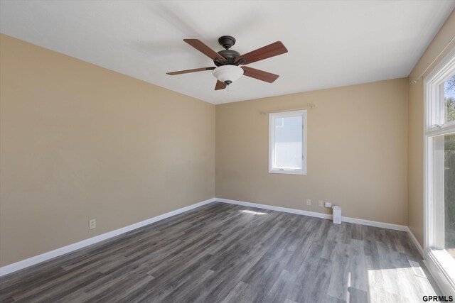 spare room with baseboards, ceiling fan, and dark wood-type flooring