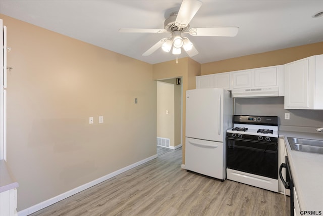 kitchen with freestanding refrigerator, gas range, under cabinet range hood, a sink, and light wood-style flooring
