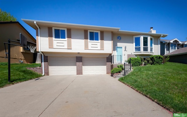 split foyer home featuring a garage, concrete driveway, a front yard, and brick siding