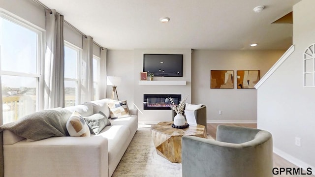 living room featuring recessed lighting, baseboards, and a glass covered fireplace