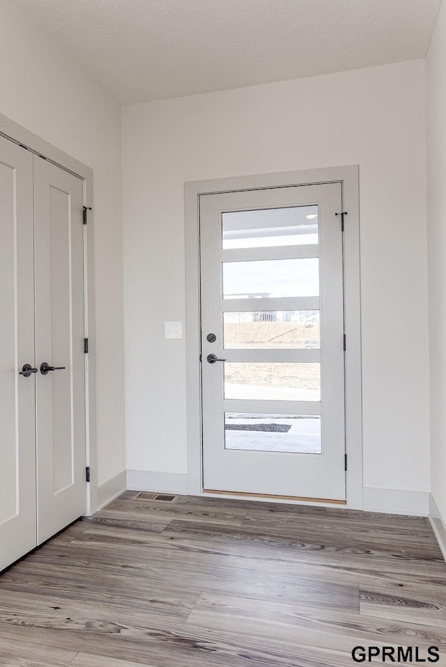 doorway featuring wood finished floors and baseboards