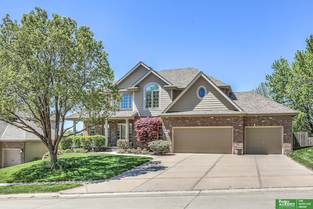 craftsman house featuring concrete driveway, brick siding, a front yard, and a garage