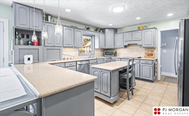 kitchen with appliances with stainless steel finishes, light tile patterned floors, gray cabinetry, and tasteful backsplash