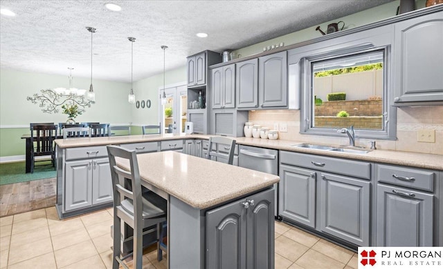 kitchen featuring a peninsula, a sink, a healthy amount of sunlight, and gray cabinets
