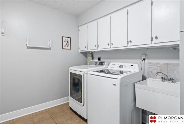 washroom featuring light tile patterned flooring, baseboards, washing machine and clothes dryer, a sink, and cabinet space
