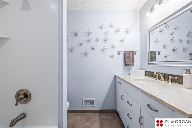 bathroom featuring a textured ceiling, visible vents, vanity, baseboards, and toilet