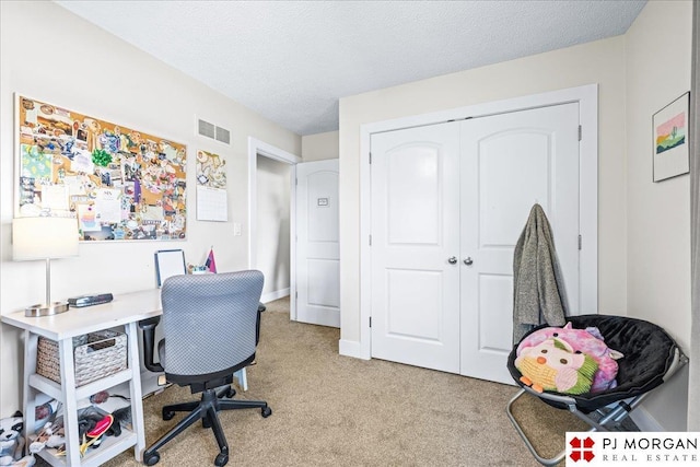 office with a textured ceiling, visible vents, and light carpet