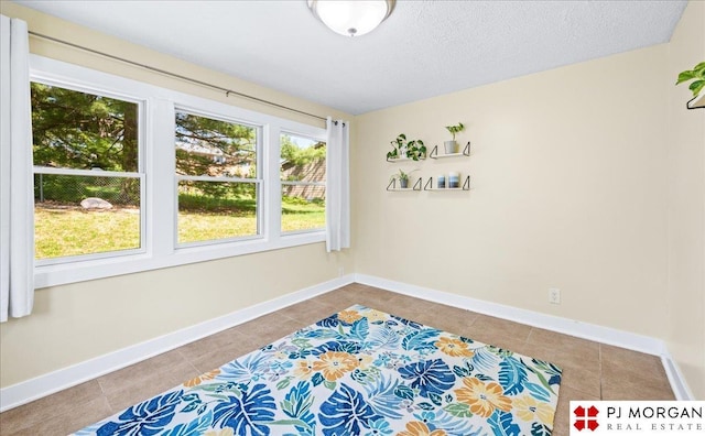 interior space with tile patterned floors, baseboards, and a textured ceiling