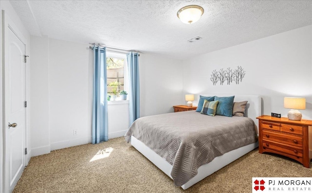 carpeted bedroom with visible vents, a textured ceiling, and baseboards