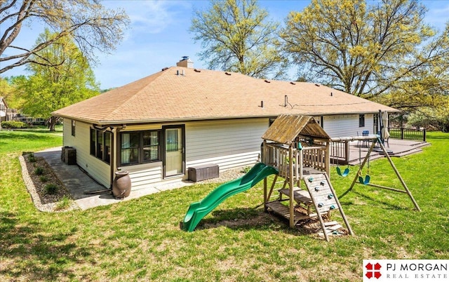 back of property featuring a chimney, roof with shingles, fence, a playground, and a yard