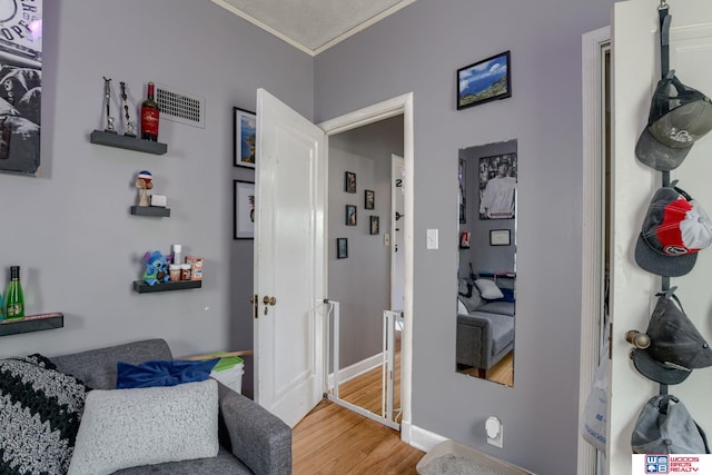 corridor featuring baseboards, visible vents, ornamental molding, and wood finished floors