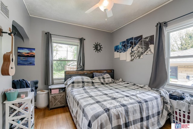 bedroom featuring crown molding, a ceiling fan, visible vents, and light wood-type flooring