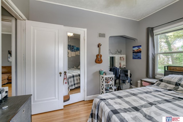 bedroom featuring ornamental molding, light wood-style flooring, and visible vents