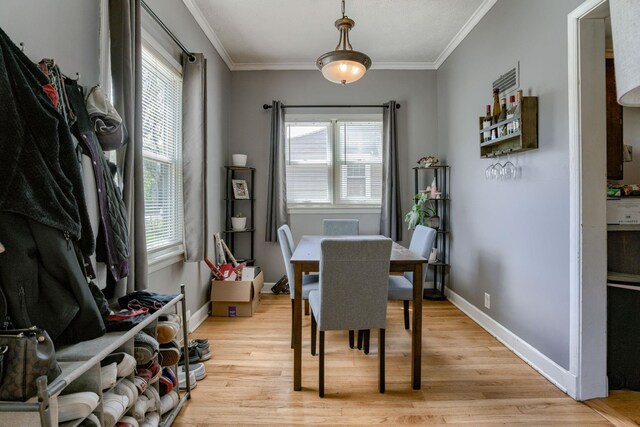dining space featuring light wood-style floors, ornamental molding, and baseboards