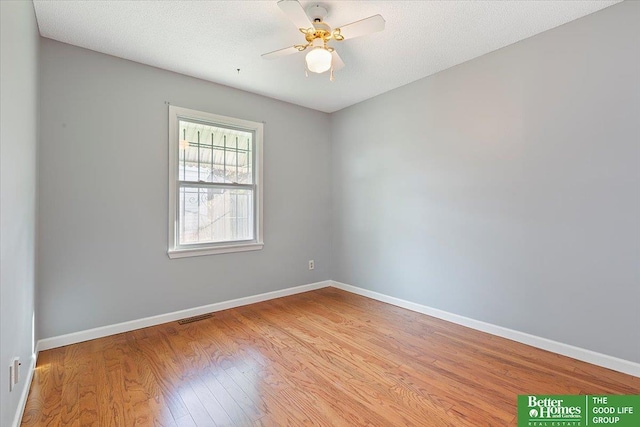 spare room with a ceiling fan, baseboards, visible vents, and wood finished floors