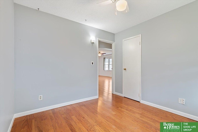 empty room with a ceiling fan, baseboards, wood finished floors, and a textured ceiling