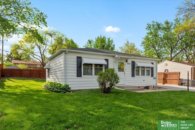 rear view of house with fence and a yard