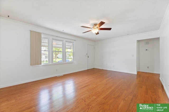 spare room with visible vents, ornamental molding, baseboards, a ceiling fan, and light wood-style flooring