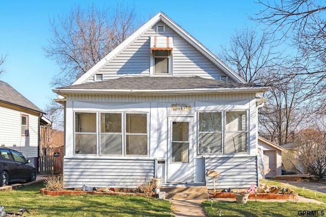 bungalow-style home with roof with shingles, a sunroom, entry steps, and a front yard