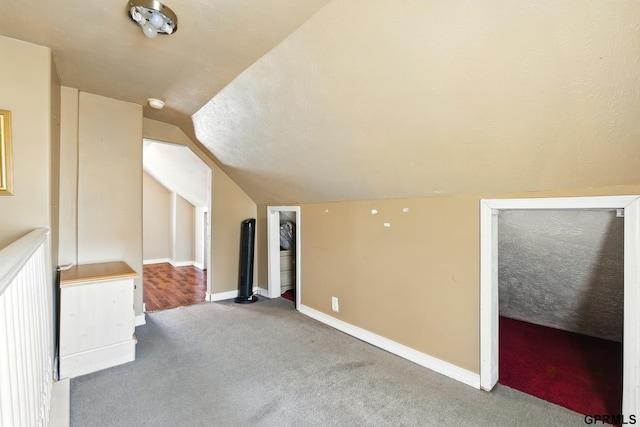 additional living space featuring baseboards, carpet, and vaulted ceiling