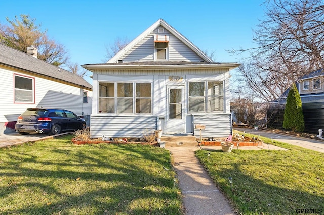 view of front of house with entry steps, a sunroom, and a front yard