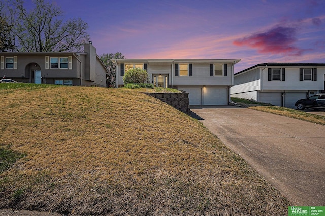 bi-level home with a lawn, an attached garage, and driveway