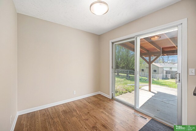 doorway with baseboards, wood finished floors, and visible vents
