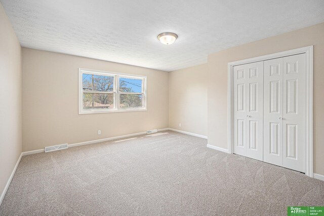 unfurnished bedroom featuring visible vents, carpet flooring, baseboards, and a closet