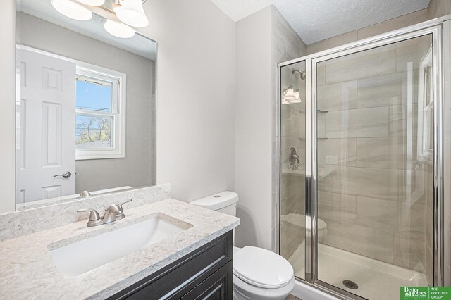 bathroom with vanity, a shower stall, toilet, and a textured ceiling