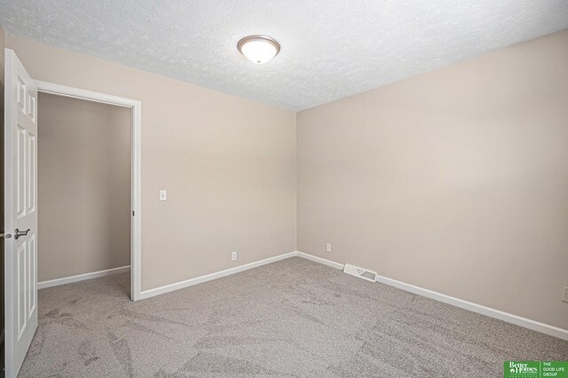 empty room with a textured ceiling, visible vents, baseboards, and carpet